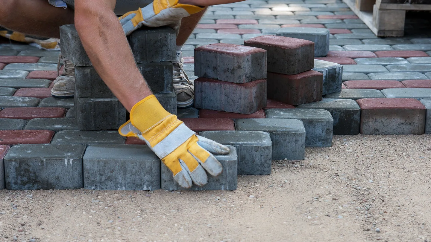 Hands setting concrete pavers into place