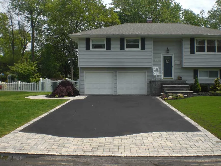 Asphalt driveway with a paver apron in front of a house